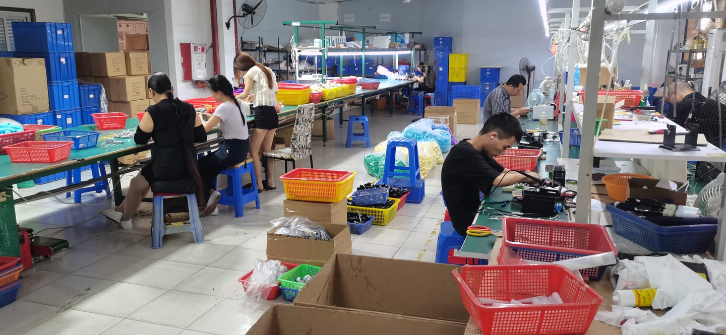 VOVOHO production floor — workers at assembly benches with coloured component bins