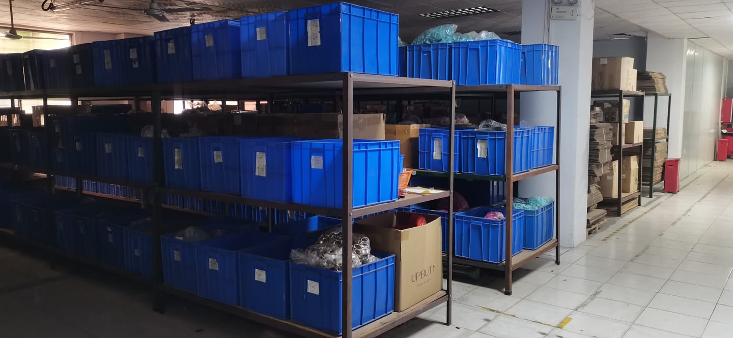 Multi-tier storage racks with labelled blue bins for component and finished-goods inventory